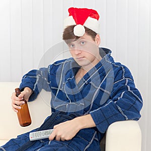 Man in Christmas cap with remote control and beer