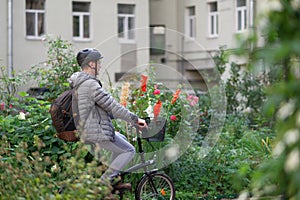 Man on a city bicycle in a city against flowers in frontage photo