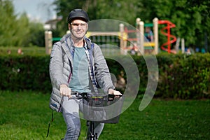 Man on a city bicycle in a city park against children playground