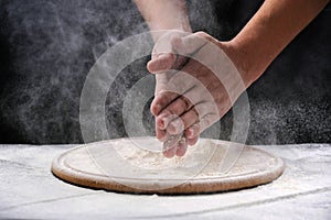 A man claps his hands with a splash of white flour and a black background. Preparing Meal, Hands in flour