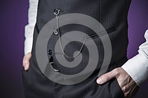 .man in classic clothes with pocket watch hanging on the vest and hands in the pockets