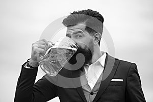 Man in classic suit drinking beer. Bearded guy in classic outfit looks happy and satisfied. Portrait of man with lifted