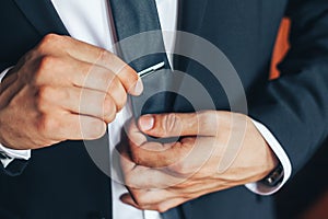 Man in a classic suit straightens his tie