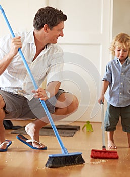 Man is cleaning with boy child, sweeping with broom and help with mess on floor while at home together. Hygiene, chores