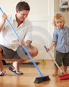 Man is cleaning with boy kid, sweeping with broom and help with mess on floor while at home together. Hygiene, chores