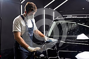 man cleaning car with cloth and detergent liquids, car detailing or valeting concept