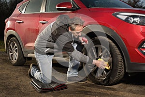 Man cleaning car outdoor and interior on dusty nature parking