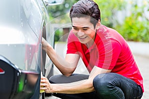 Man cleaning car rims with sponge