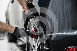 Man cleaning car wheel with brush