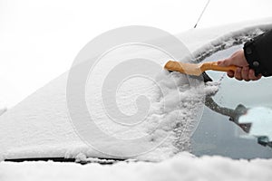 Man cleaning car windshield from snow