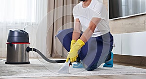 Man Cleaning Carpet In The Living Room Using Vacuum Cleaner At Home. Cleaning service concept