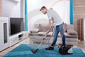 Man Cleaning Carpet With Vacuum Cleaner