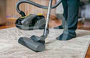 Man is cleaning carpet with vacuum cleaner