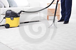 Man cleaning carpet with vacuum cleaner, closeup