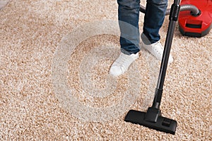 Man cleaning carpet with vacuum cleaner at home, closeup. Space for text