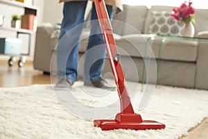 Man cleaning carpet with a vacuum cleaner in room