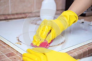 Man cleaning ceramic modern stove or hob with detergent agent. Hand in yellow gloves clean stove from burnt and grease dirt.