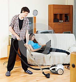 Man cleaning with cleaner during woman over sofa