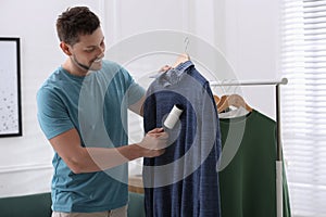 Man cleaning clothes with lint roller indoors