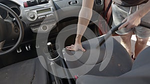 Man cleaning dirty car interior with vacuum cleaner