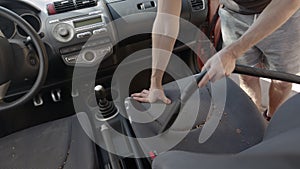 Man cleaning dirty car interior with vacuum cleaner