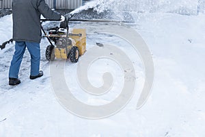 Man cleaning driveway with snow machines after a snow storm. Snow removal equipment working on the street. Cleaning of