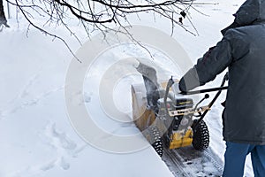 Man cleaning driveway with snow machines after a snow storm. Snow removal equipment working on the street. Cleaning of