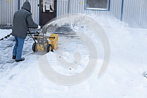 Man cleaning driveway with snow machines after a snow storm. Snow removal equipment working on the street. Cleaning of