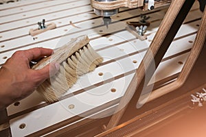 Man is cleaning dust from computer numerical control machine for wooden tools. CNC equipment for maintenance control and details