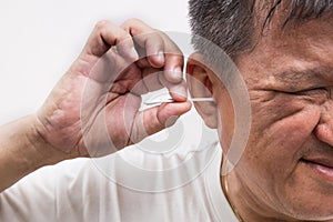 Man cleaning ear with cotton buds stick with ticklish expression