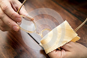 Man is cleaning eye glasses with a microfibre cloth, hornrims