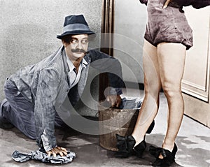 Man cleaning the floor looking at the legs of a woman