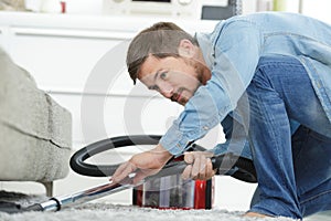 man cleaning floor under bed with vacuum cleaner