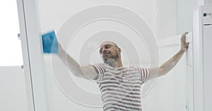 Man cleaning glass surface in modern apartment, servant cleaning glass surface