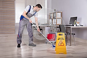 Man Cleaning Hardwood Floor In Office