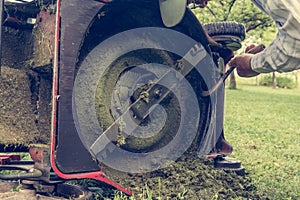 Man cleaning lawn mower blade.