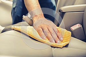 A man cleaning leather car seat with microfiber cloth photo