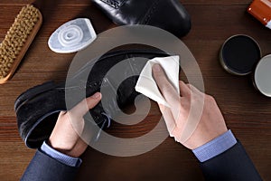 Man cleaning leather shoe at wooden table