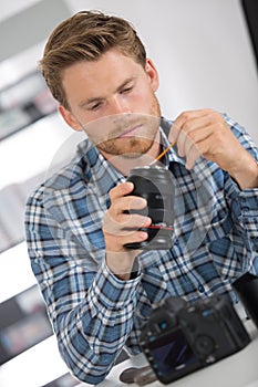 Man cleaning lens digital camera with special brush