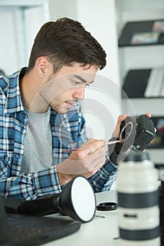 Man cleaning lens digital camera with special brush