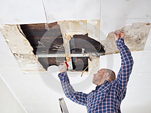 Man cleaning mold on ceiling.