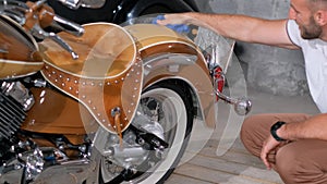 Man cleaning motor vehicle with tire, wheel, fender, hood in garage