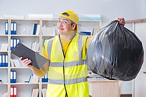 The man cleaning the office and holding garbage bag