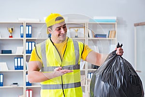 The man cleaning the office and holding garbage bag