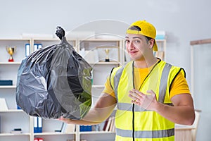 The man cleaning the office and holding garbage bag