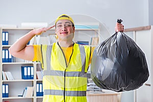 The man cleaning the office and holding garbage bag