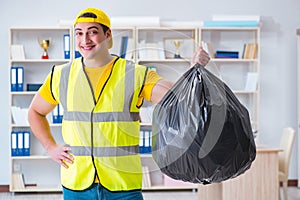 The man cleaning the office and holding garbage bag