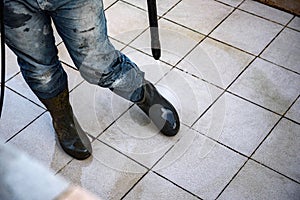 A man is cleaning the overshoes using a high-pressure washer.