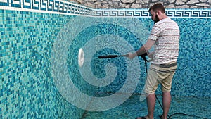 A man is cleaning the pool wall