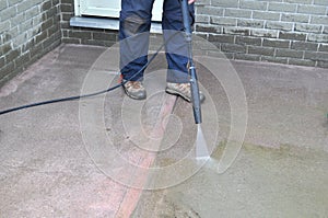 Man cleaning a sidewalk with a pressure washer during spring yard and garden work
